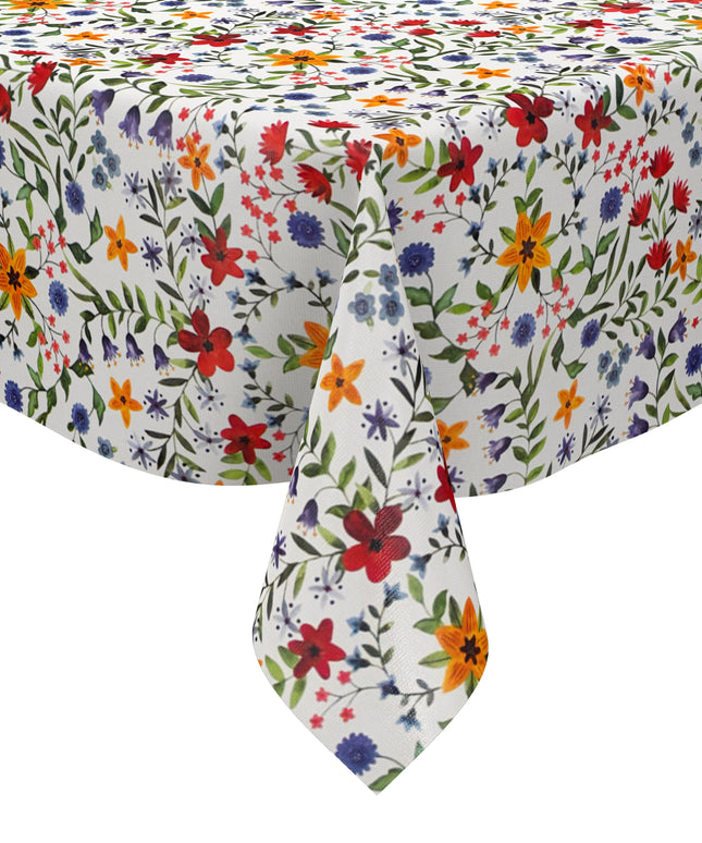 Weiße Wachstuch-Tischdecke mit dichtem, farbenfrohem Wildblumenmuster. Rote, gelbe, orangefarbene, blaue und violette Blüten sowie grüne Blätter und Ranken verteilen sich gleichmäßig über die gesamte Oberfläche und erinnern an eine blühende Sommerwiese im Landhausstil. Die rechteckige Tischdecke ist dekorativ über einen Tisch drapiert.