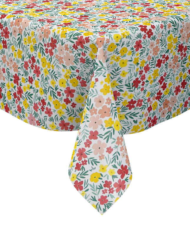 Bunte Wachstuch-Tischdecke mit dichtem Streublumenmuster in Rot, Gelb und Rosa sowie grünen Blättern auf hellem Hintergrund, über eine rechteckige Tischkante drapiert.