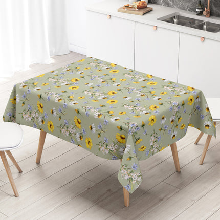 Wachstuch-Tischdecke mit Wiesenblumenmuster auf salbeigrünem Hintergrund. Gelbe Blüten, weiße Margeriten, kleine blaue Blumen und zarte weiße Blütenzweige sind gleichmäßig verteilt und sorgen für eine frische, natürliche Ausstrahlung.
