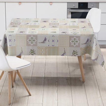 Wachstuch-Tischdecke mit Patchwork-Muster in Creme, Beige und Grau. Dekorative Fliesenornamente, stilisierte Blüten, Lavendel- und Olivenzweige in sanften Grün- und Lilatönen verleihen dem Design einen mediterranen Landhaus-Charme.