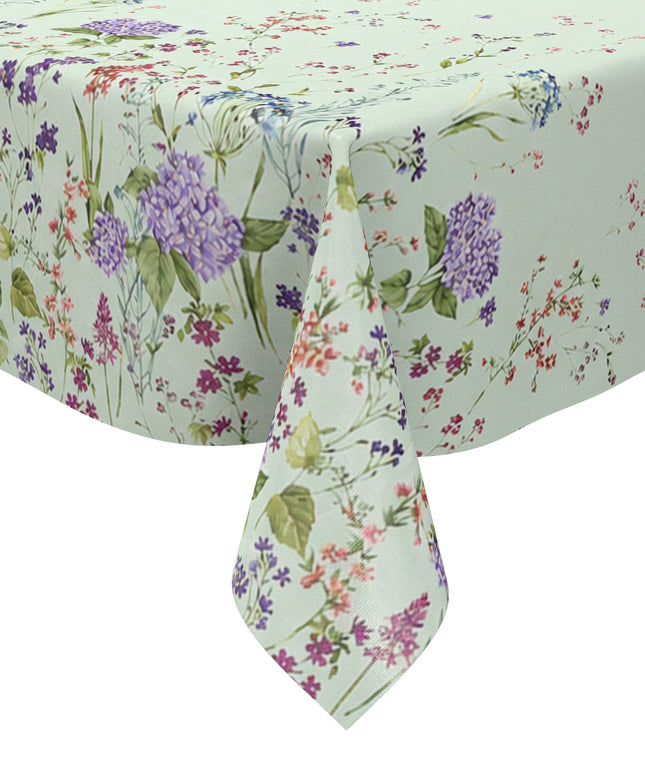 Wachstuchtischdecke mit romantischem Blumenmuster auf mintgrünem Hintergrund. Zarte Wildblumen, filigrane Zweige und Blütenranken in Rosa, Blau, Lila und Rot verteilen sich locker über die Fläche. Große violette Hortensien setzen dekorative Akzente entlang der oberen und unteren Bereiche. Das detailreiche, aquarellartige Dessin wirkt leicht, natürlich und verspielt und verleiht dem Tisch eine frische, florale Ausstrahlung.