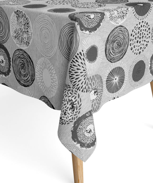Jacquard-Tischdecke mit grafischem Kreismotiv aus Spiralen, Punkten, Strahlen und floralen Formen in Grau, Weiß und Anthrazit.
