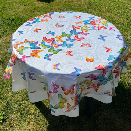 bedruckte Folie mit bunten Schmetterlingen auf einer weißen Stofftischdecke mit floralem Muster fotografiert