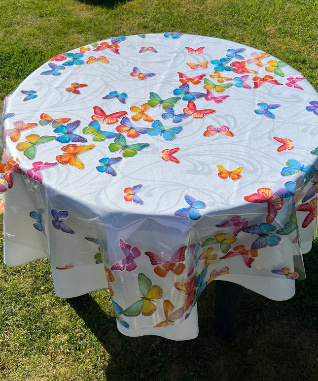 bedruckte Folie mit bunten Schmetterlingen auf einer weißen Stofftischdecke mit floralem Muster fotografiert
